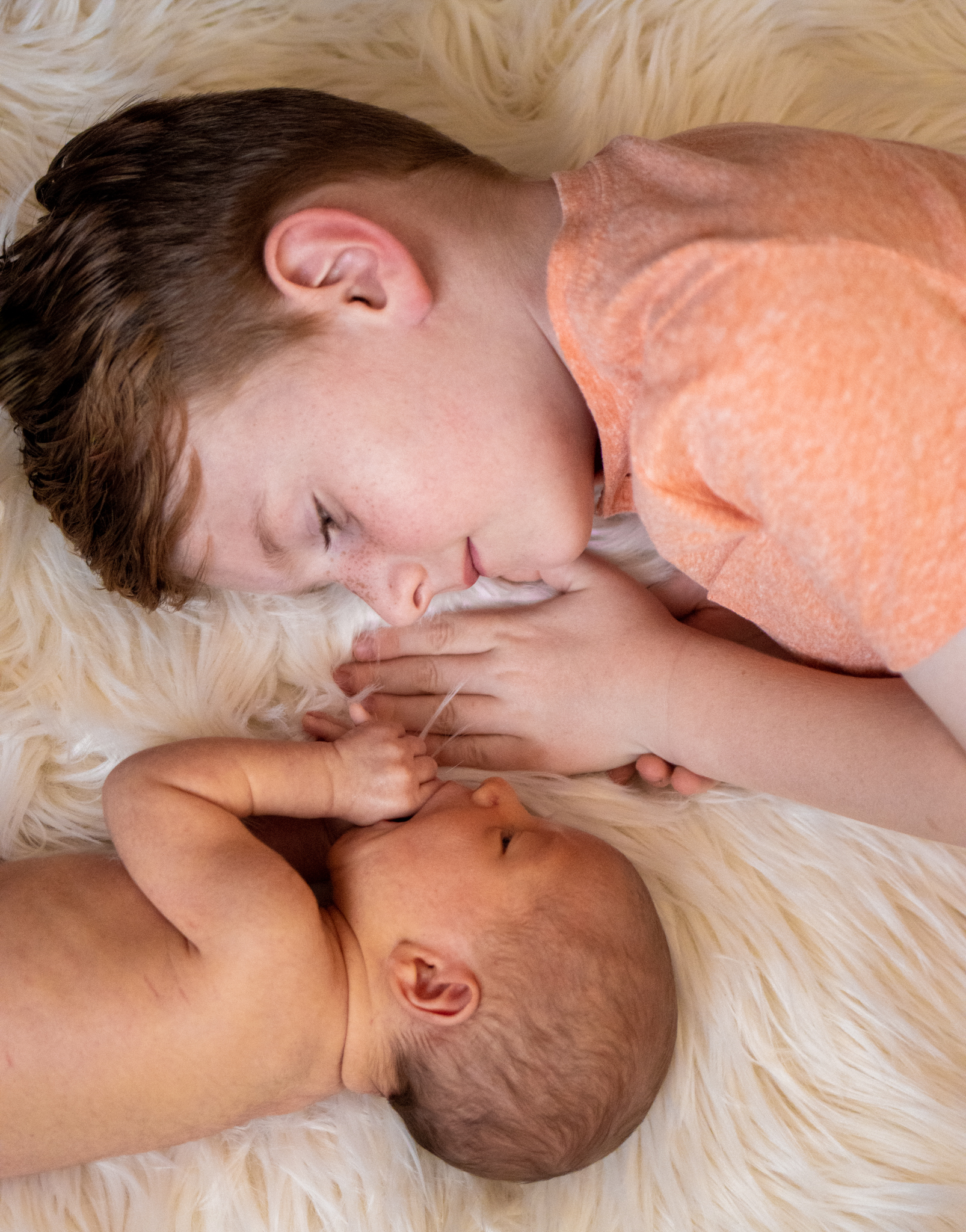 Toddler and Newborn Baby Lying Down, Facing Each Other