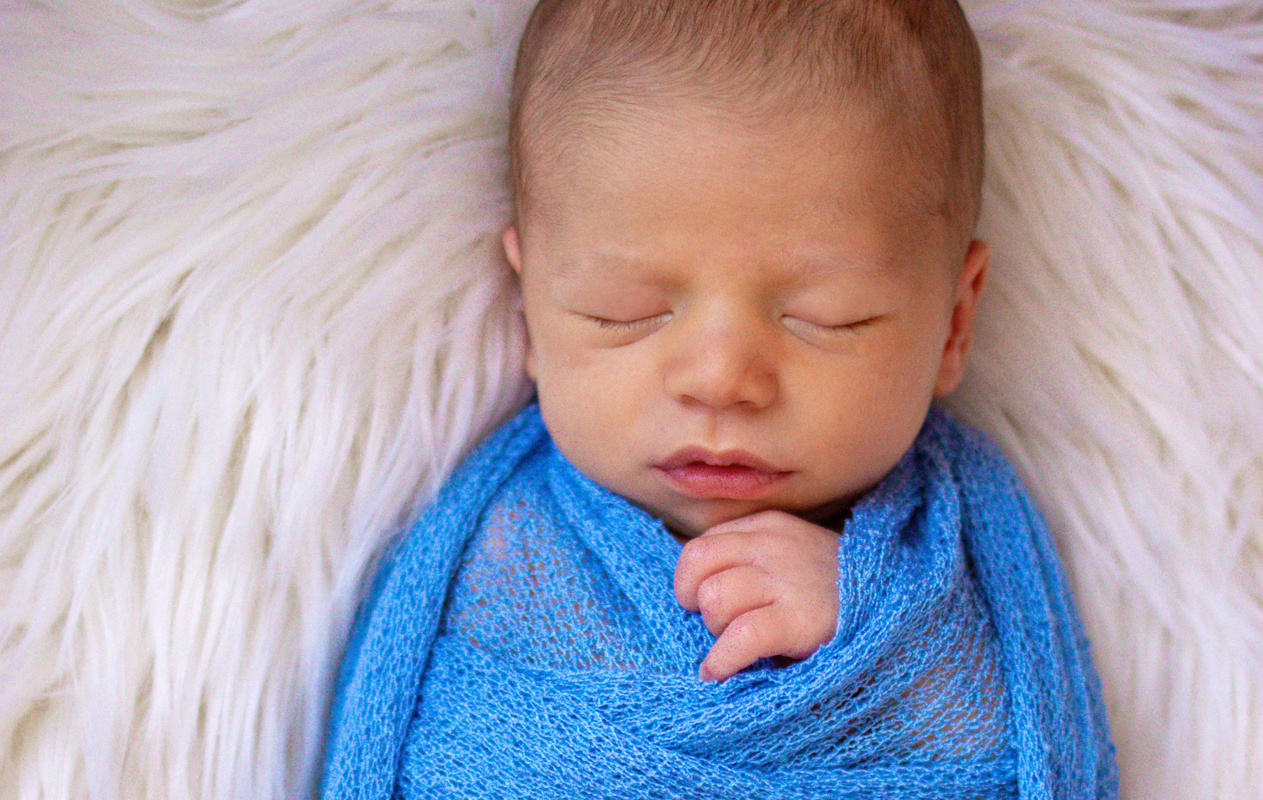 Sleeping Newborn Baby Wrap in a Blue Blanket