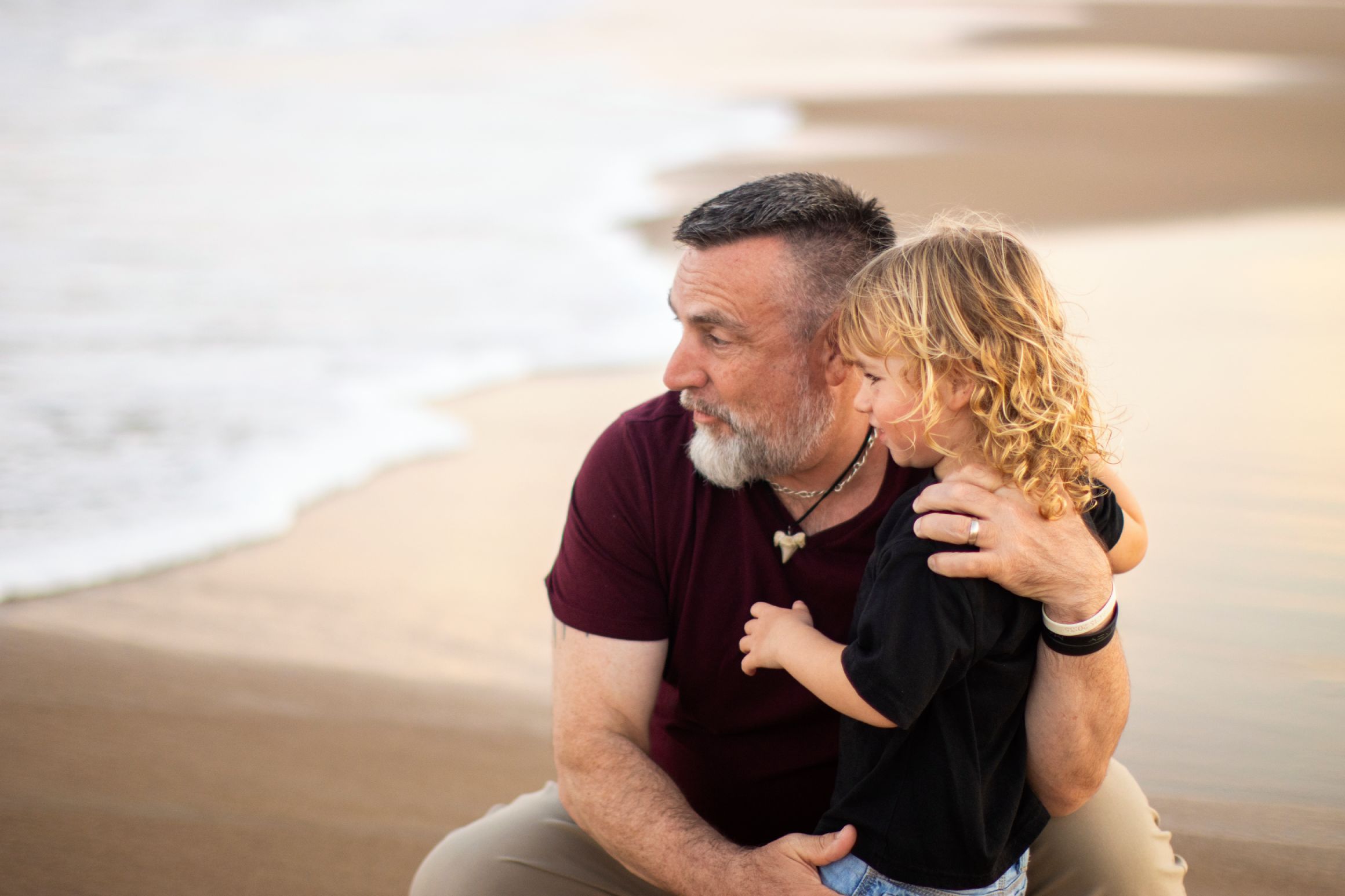 Father and daughter pose in beach during their annual family photo session