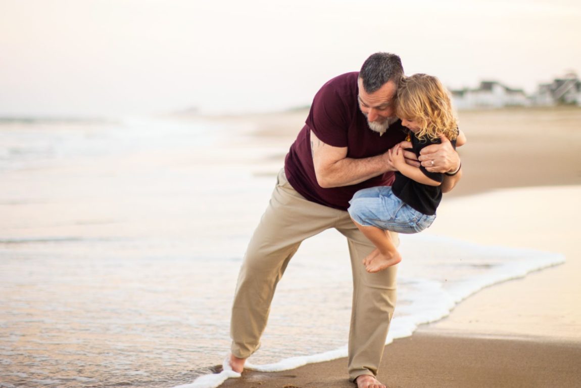 Are annual family photos worth it? A father carrying his daughter near the shore during a family photo session.