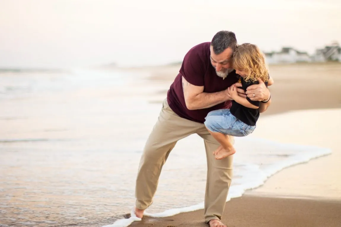 Are annual family photos worth it? A father carrying his daughter near the shore during a family photo session.