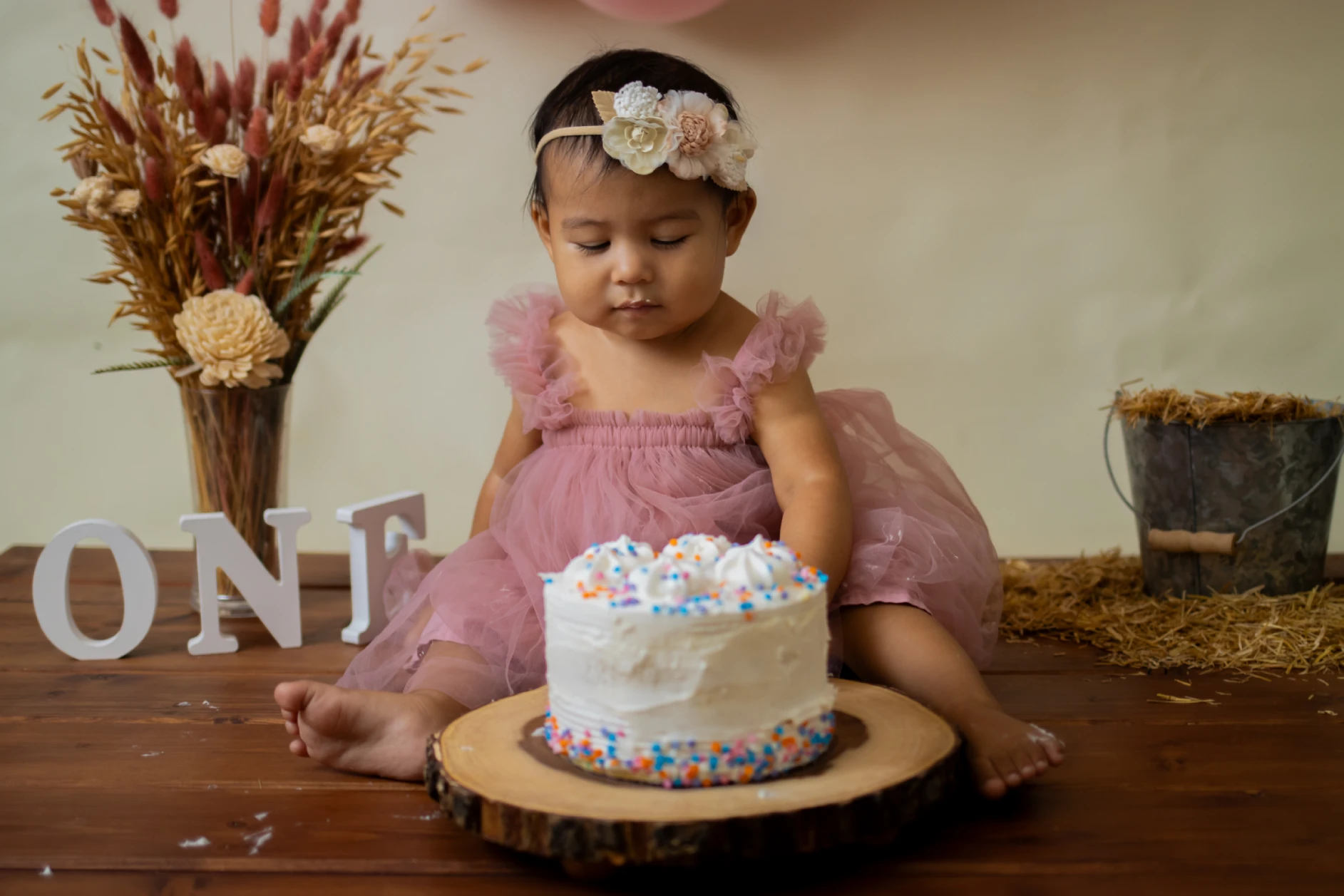 Cake smash theme session set in a brown field scenery, capturing a joyful baby enjoying a cake smash outdoors.