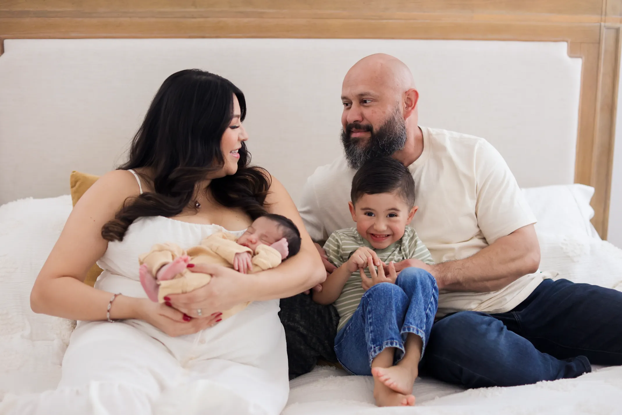 Family of four with newborn and toddler cuddled together perfect for a family movie night photo slideshow