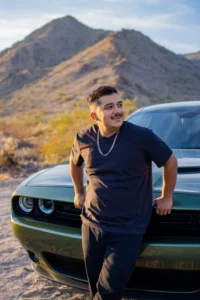 Senior guy posing in front of a muscle car during a golden hour desert session in Phoenix