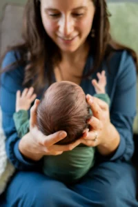 Mom smiling down at her newborn during an in-home newborn session in the West Valley
