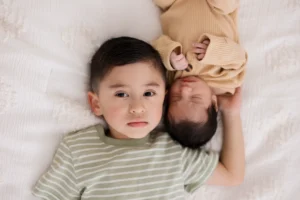 Toddler lying next to sleeping newborn during an in-home newborn photography session in the West Valley