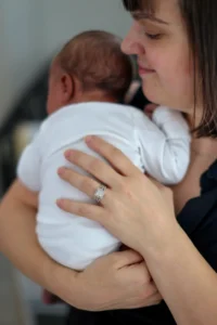 Mom gently holding her newborn close, the kind of tender moment that makes newborn photos worth it