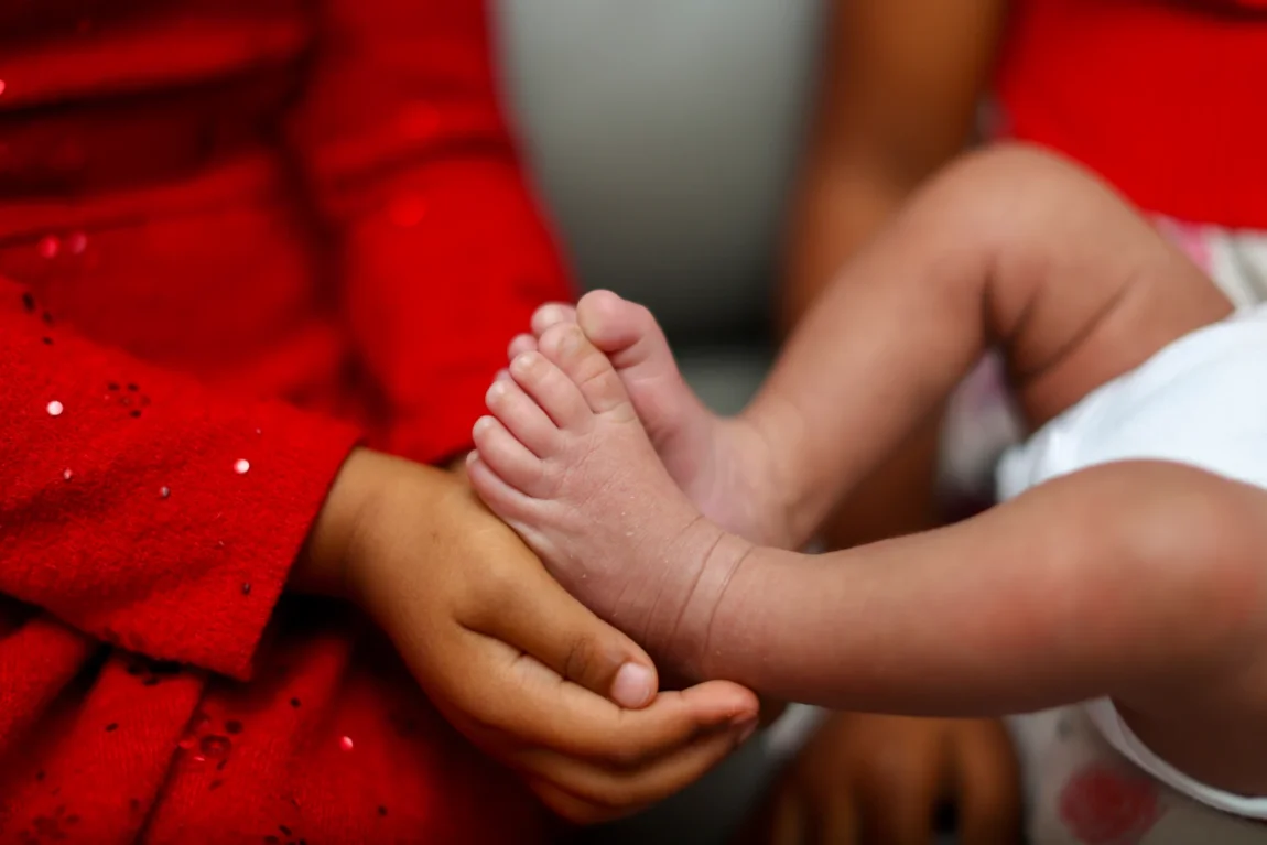 Close-up of newborn baby feet cradled in a parent's hands, a detail worth capturing in professional newborn photos