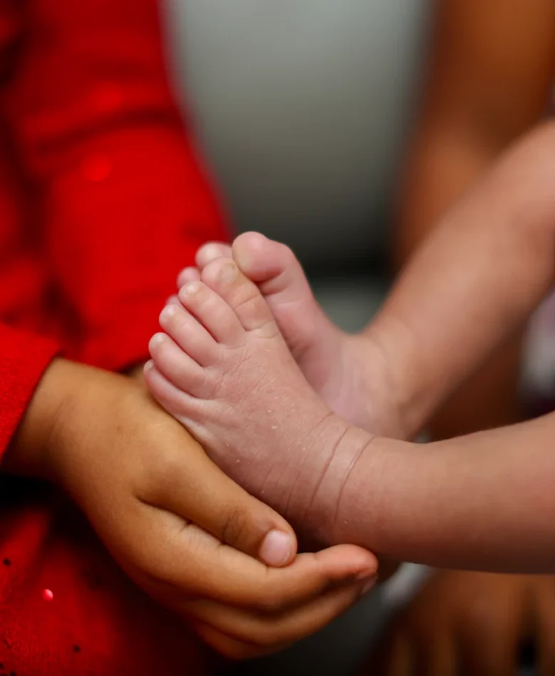 Close-up of newborn baby feet cradled in a parent's hands, a detail worth capturing in professional newborn photos