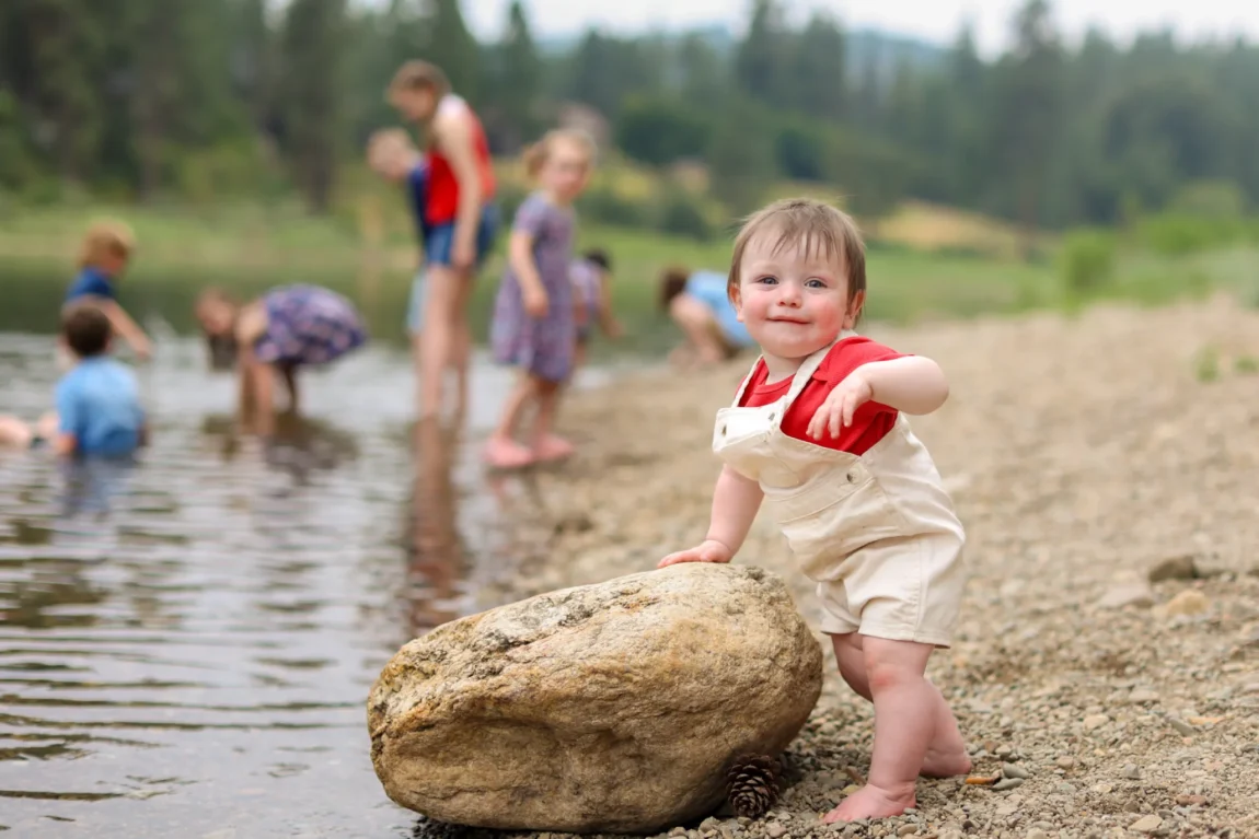 Toddler boy smiling by a creek, a family photo worth learning how to arrange on a wall