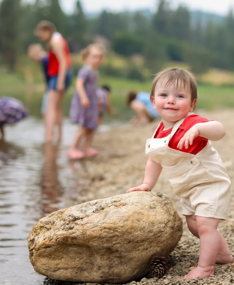 Toddler boy smiling by a creek, a family photo worth learning how to arrange on a wall