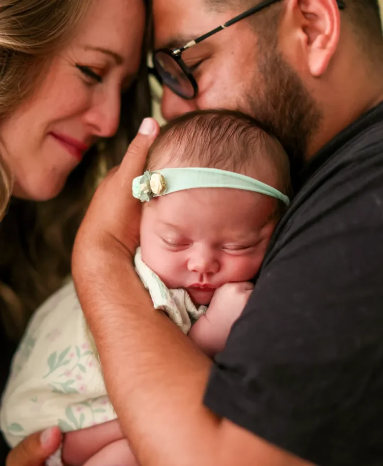 Parents leaning in close over their sleeping newborn during an in-home newborn session in Verrado