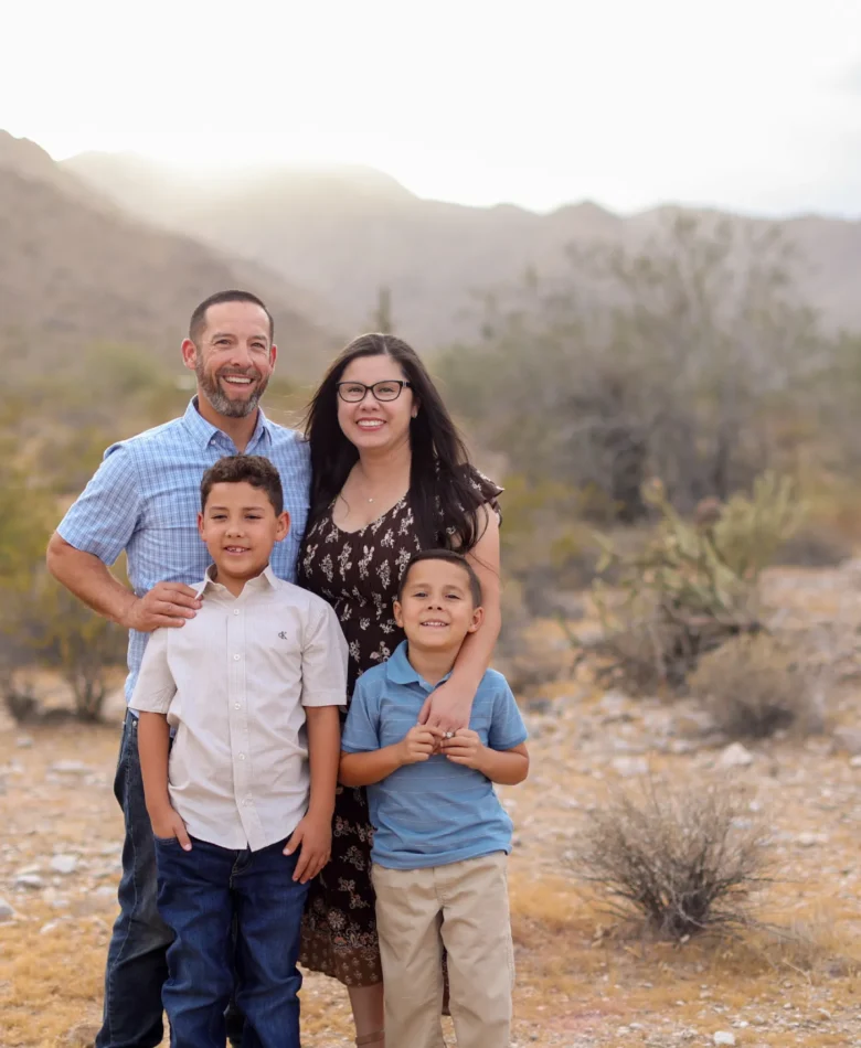 Family of four smiling together during fall family photos in the West Valley desert mountains