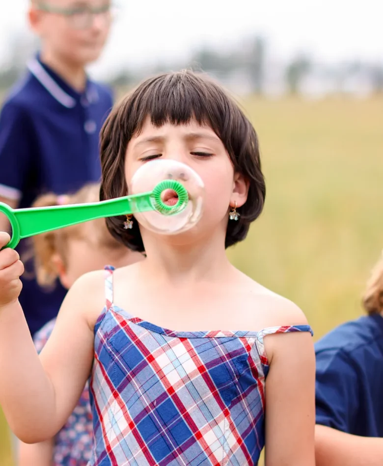 A little girl blows bubbles while her siblings wander nearby, proof that when you prepare for family photos the right way, nothing needs to be forced.