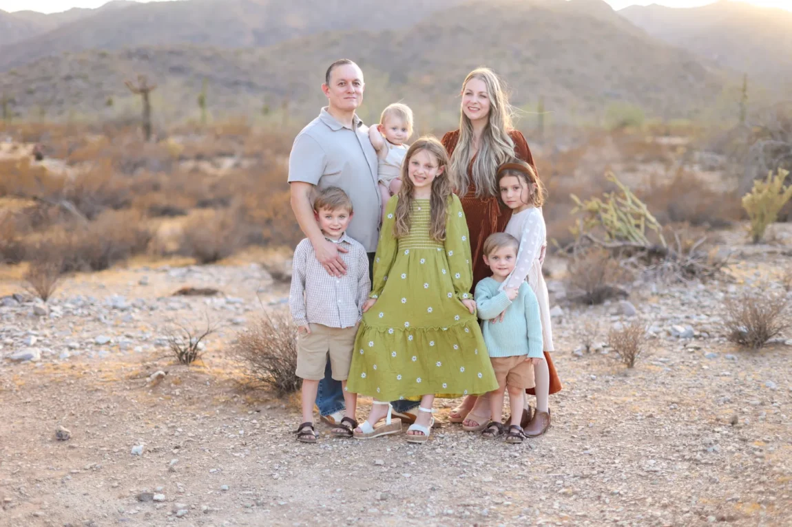Family of seven posing together during holiday card photos in Phoenix desert at golden hour
